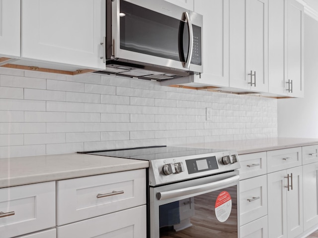 kitchen featuring backsplash, hardwood / wood-style floors, appliances with stainless steel finishes, and white cabinets