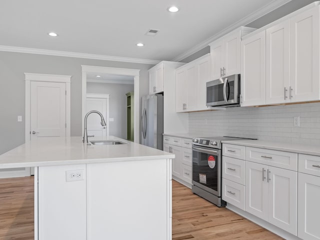 kitchen with white cabinets, stainless steel appliances, a center island with sink, and sink