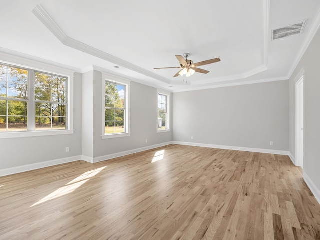 empty room featuring ornamental molding, a tray ceiling, light wood-type flooring, and ceiling fan