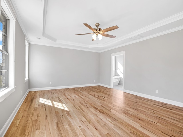 spare room featuring ornamental molding, a tray ceiling, and light wood-type flooring