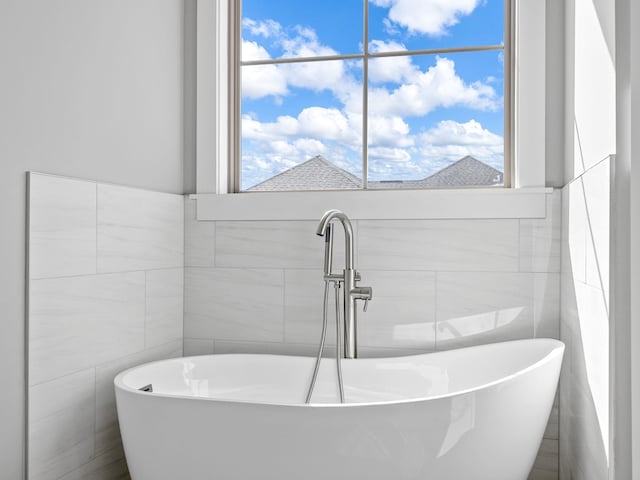 bathroom with tile walls, sink, and a bathing tub