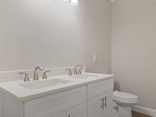 bathroom with toilet, vanity, and tile patterned floors