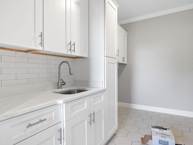 kitchen featuring sink, backsplash, light stone counters, white cabinets, and crown molding