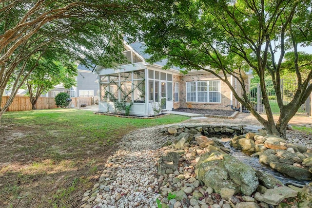 rear view of house with a lawn and a sunroom