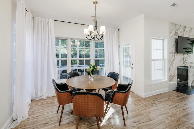 dining area featuring a wealth of natural light, ornamental molding, a chandelier, and light wood-type flooring