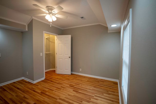 unfurnished bedroom featuring a spacious closet, a closet, ceiling fan, light hardwood / wood-style floors, and ornamental molding