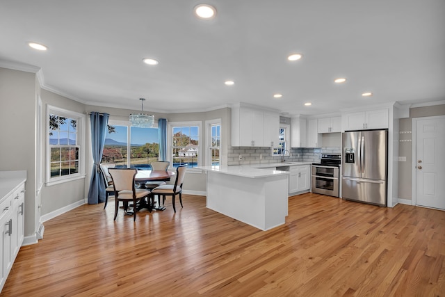 kitchen featuring plenty of natural light, white cabinets, stainless steel appliances, and decorative light fixtures