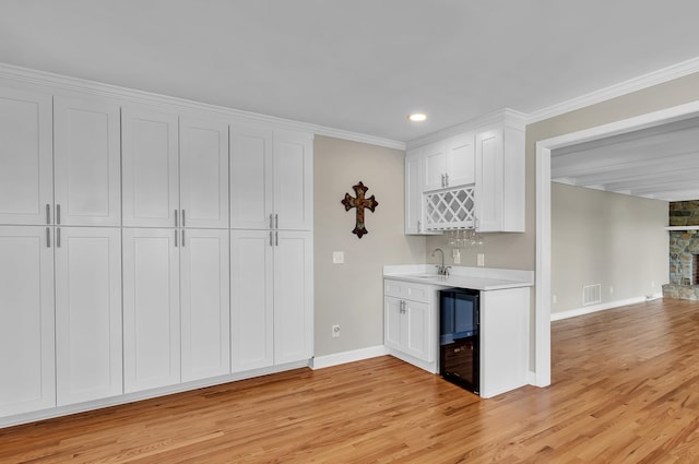 kitchen featuring ornamental molding, sink, white cabinetry, and beverage cooler