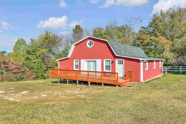 rear view of property featuring a wooden deck and a lawn