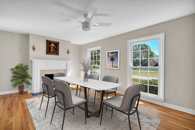 dining space with ceiling fan, light hardwood / wood-style flooring, plenty of natural light, and a fireplace