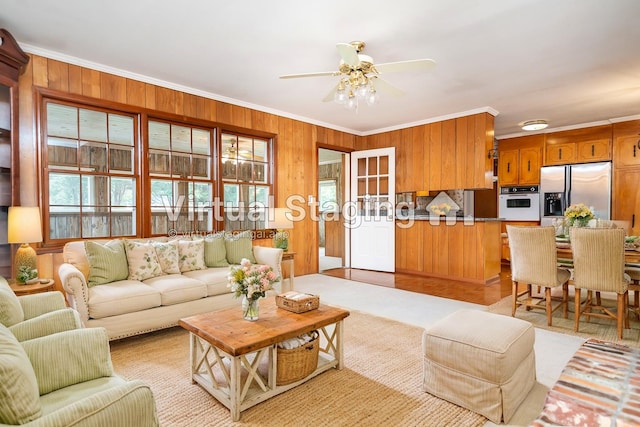 living room with crown molding, wood walls, and ceiling fan