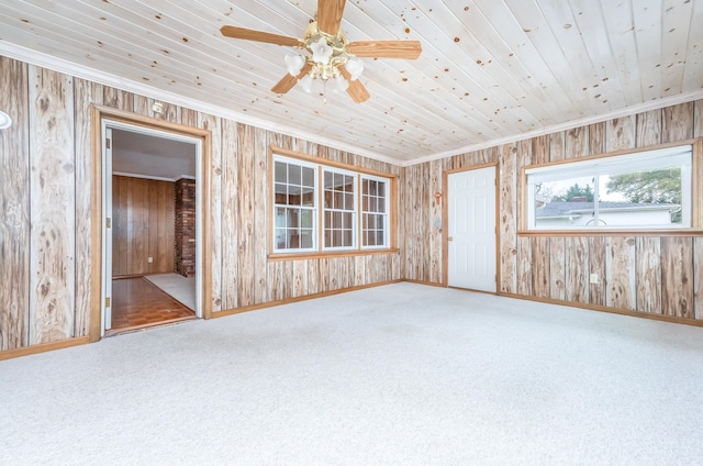 empty room featuring ceiling fan, carpet flooring, ornamental molding, and wooden walls