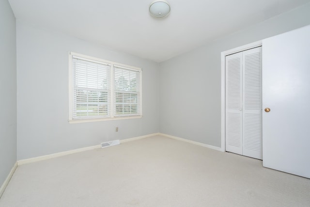 unfurnished bedroom featuring a closet and light colored carpet