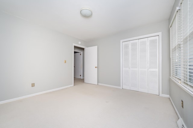 unfurnished bedroom featuring a closet and light colored carpet