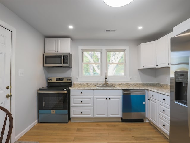 kitchen featuring sink, white cabinets, stainless steel appliances, and light hardwood / wood-style floors