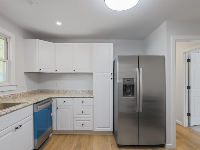 kitchen with light stone countertops, appliances with stainless steel finishes, light hardwood / wood-style flooring, and white cabinets