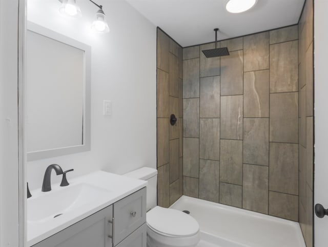 bathroom featuring toilet, vanity, and a tile shower