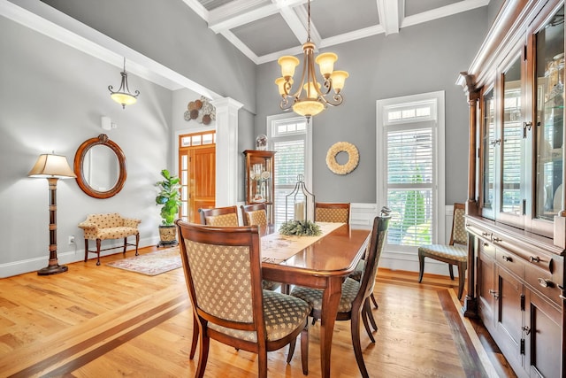 dining space with a chandelier, decorative columns, light hardwood / wood-style flooring, ornamental molding, and coffered ceiling