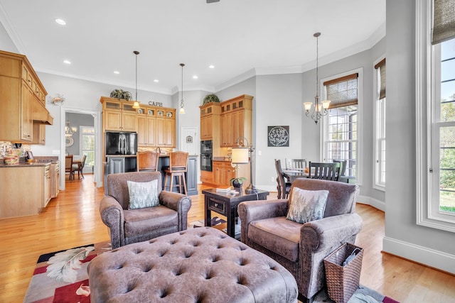 living room with crown molding, a chandelier, and light wood-type flooring