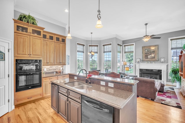 kitchen with an island with sink, dishwasher, light hardwood / wood-style floors, crown molding, and sink