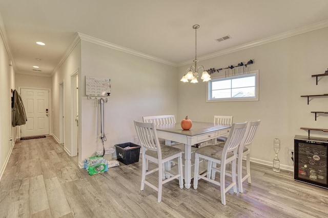 dining room featuring light hardwood / wood-style floors, crown molding, and a chandelier