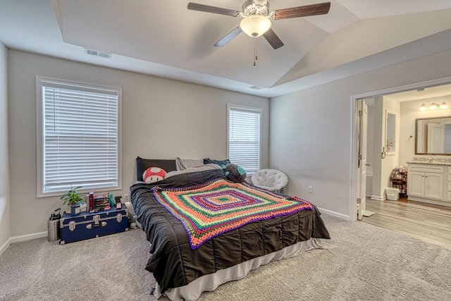 carpeted bedroom with ensuite bath, lofted ceiling, and ceiling fan