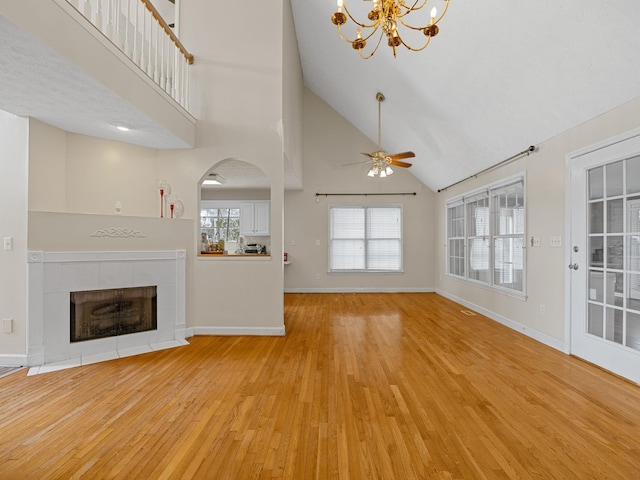 unfurnished living room featuring light hardwood / wood-style floors, high vaulted ceiling, plenty of natural light, and ceiling fan