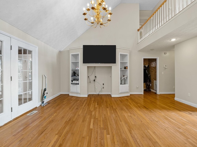 unfurnished living room with high vaulted ceiling, a textured ceiling, light wood-type flooring, and built in shelves