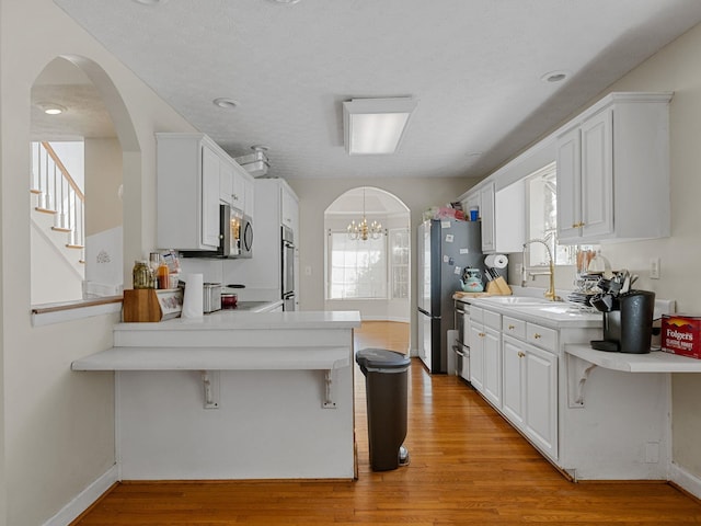 kitchen with kitchen peninsula, white cabinets, stainless steel appliances, and plenty of natural light