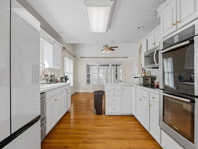 kitchen featuring light hardwood / wood-style flooring, stainless steel appliances, white cabinets, a textured ceiling, and ceiling fan