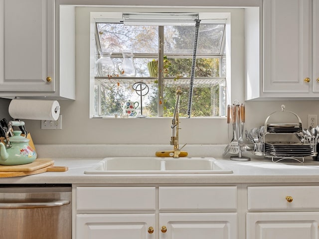 kitchen featuring white cabinets, stainless steel dishwasher, and sink