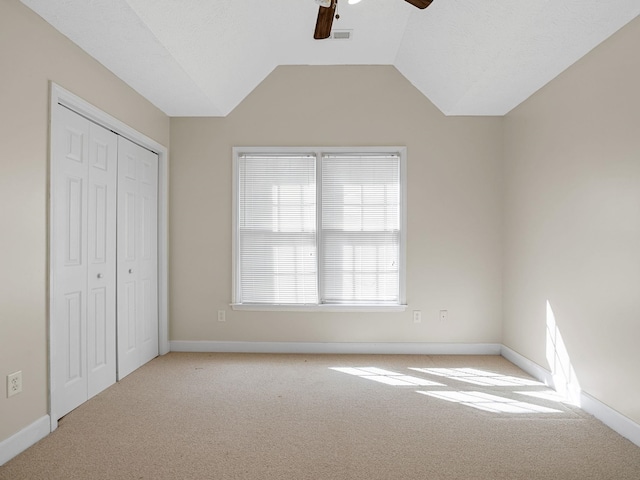 unfurnished bedroom featuring vaulted ceiling, light carpet, a closet, and ceiling fan