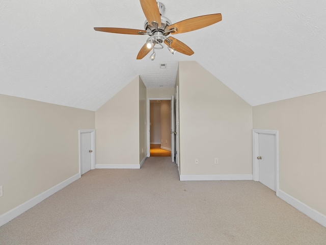 additional living space featuring lofted ceiling, light carpet, a textured ceiling, and ceiling fan