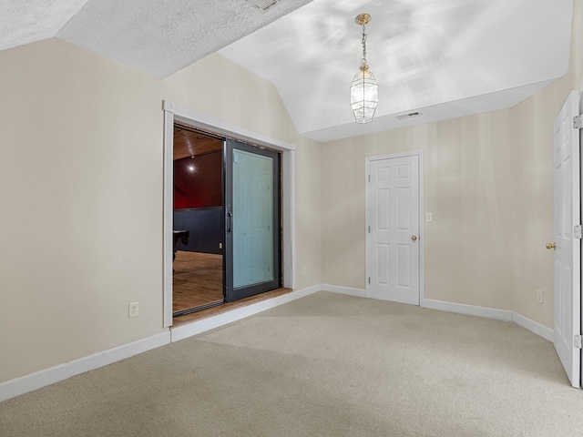 spare room featuring lofted ceiling, a textured ceiling, and carpet floors