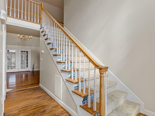 stairs featuring hardwood / wood-style floors, a high ceiling, and a chandelier