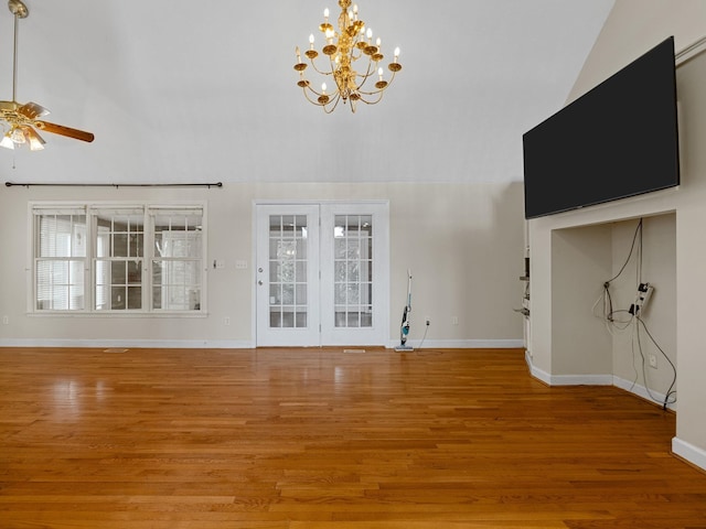 unfurnished living room featuring hardwood / wood-style floors, ceiling fan with notable chandelier, and a high ceiling