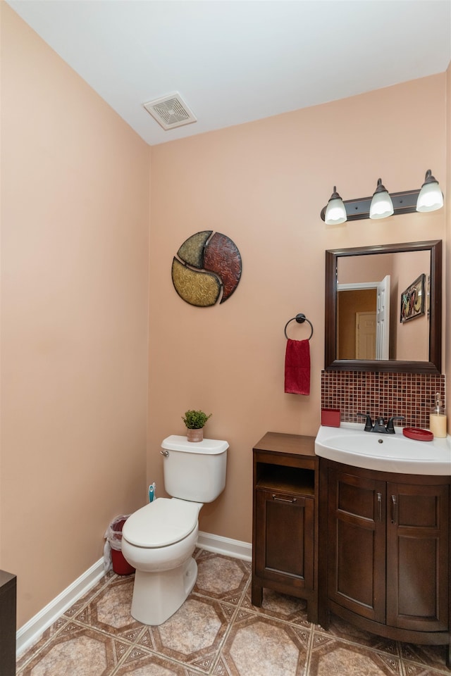 bathroom with toilet, vanity, and backsplash