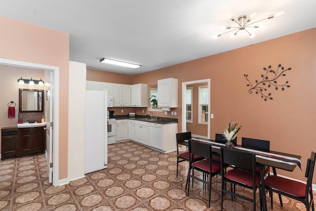 kitchen featuring sink, a chandelier, white cabinets, and white appliances