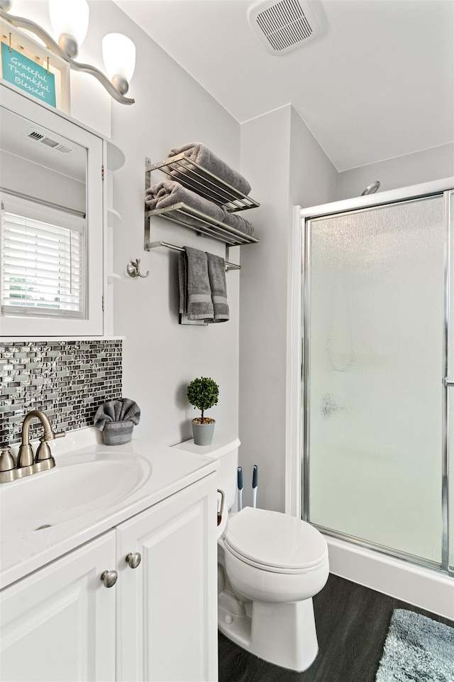 bathroom with decorative backsplash, hardwood / wood-style flooring, toilet, vanity, and an enclosed shower