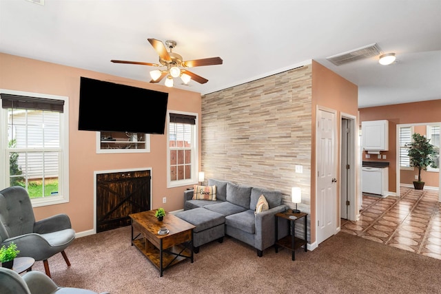 living room with ceiling fan, light carpet, and a tile fireplace