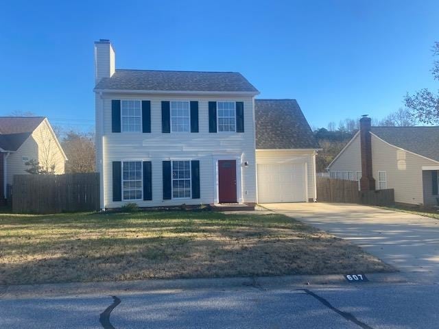 colonial home featuring a front yard and a garage