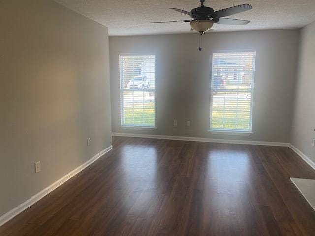 spare room featuring ceiling fan, dark wood-type flooring, and a wealth of natural light