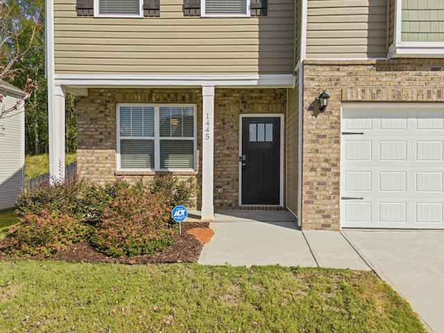 view of exterior entry featuring a lawn and a garage