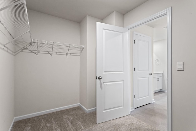 walk in closet featuring light colored carpet