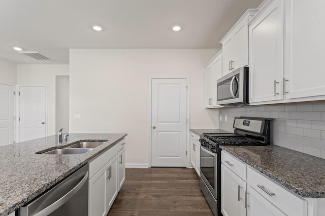 kitchen featuring dark hardwood / wood-style floors, dark stone counters, sink, white cabinets, and appliances with stainless steel finishes