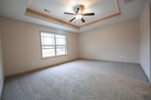 carpeted empty room featuring ceiling fan and a raised ceiling