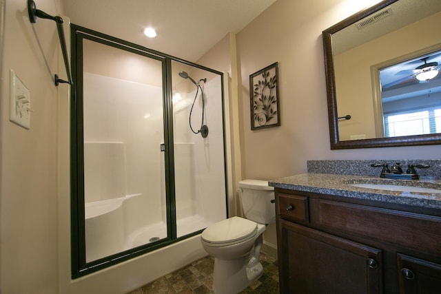 bathroom with walk in shower, ceiling fan, vanity, and toilet