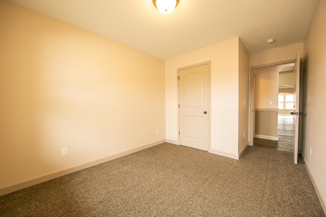 unfurnished bedroom featuring a textured ceiling and dark carpet