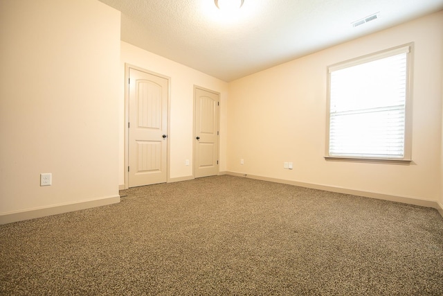 carpeted spare room with a textured ceiling