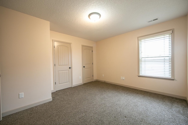 carpeted empty room with a textured ceiling